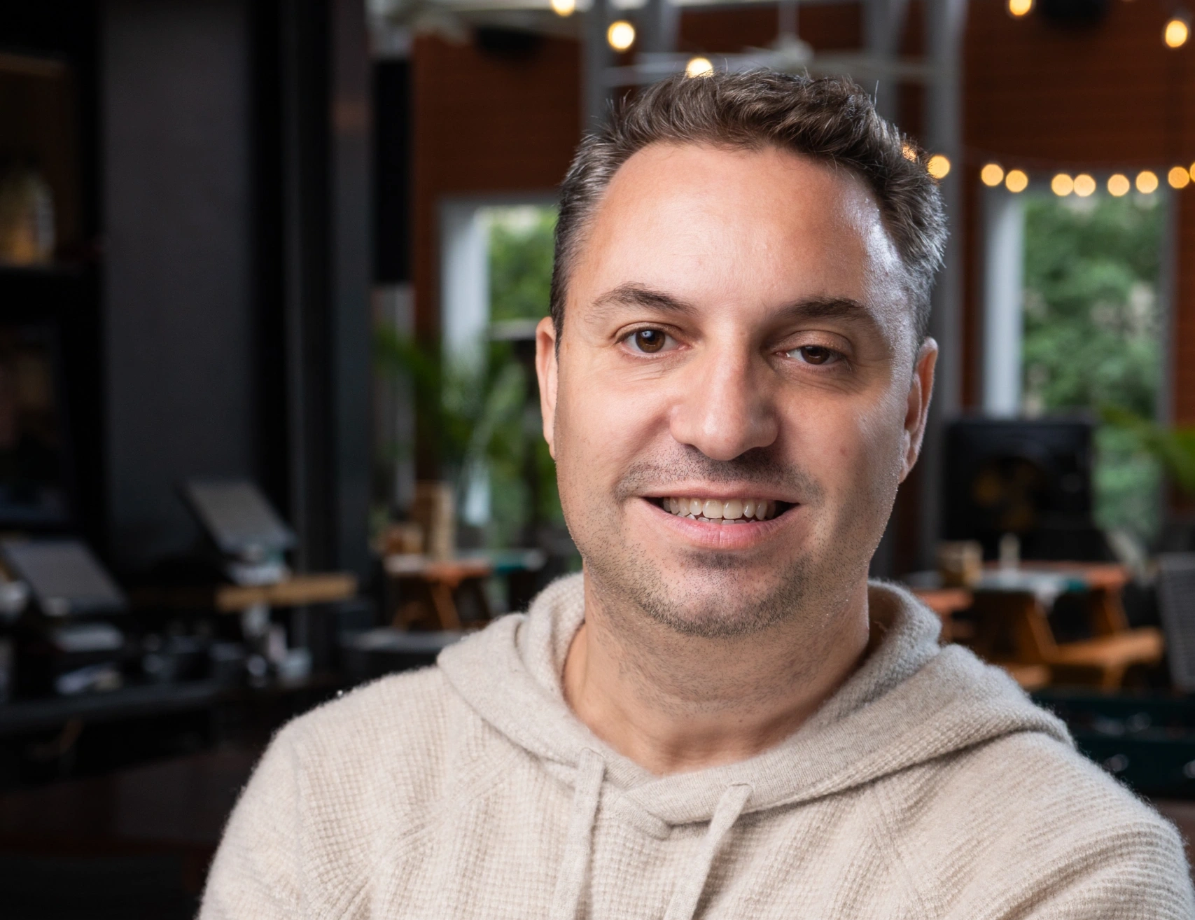 Smiling man in a casual sweater at a cozy cafe - Opus1: Everything You Need to Run Your School in One Place