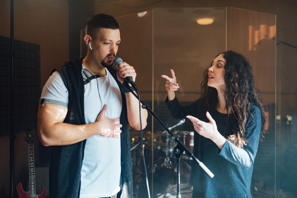 A vocal coach works closely with a student during a voice lesson, focusing on technique and expression.