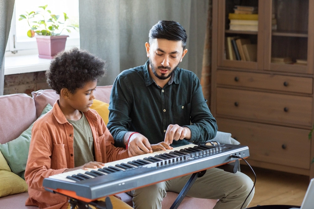 A piano teacher gives individualized instruction to a young student during a one-on-one keyboard lesson at home.