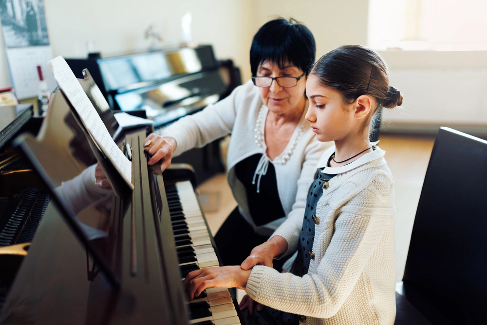 A young piano student receives focused instruction from her teacher during a one-on-one lesson.
