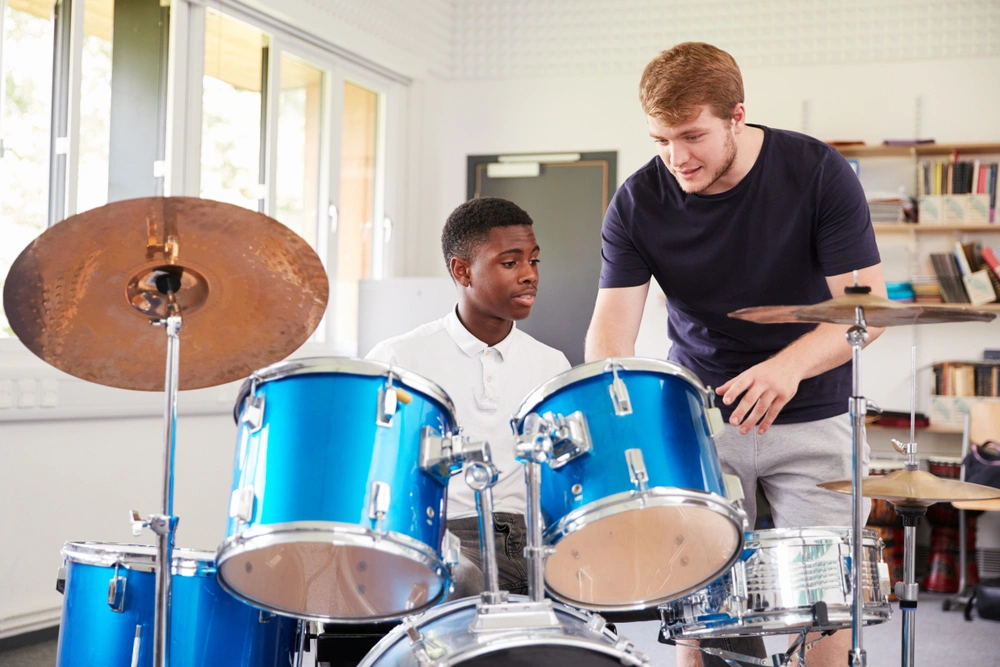 A man showing a boy how to play drums