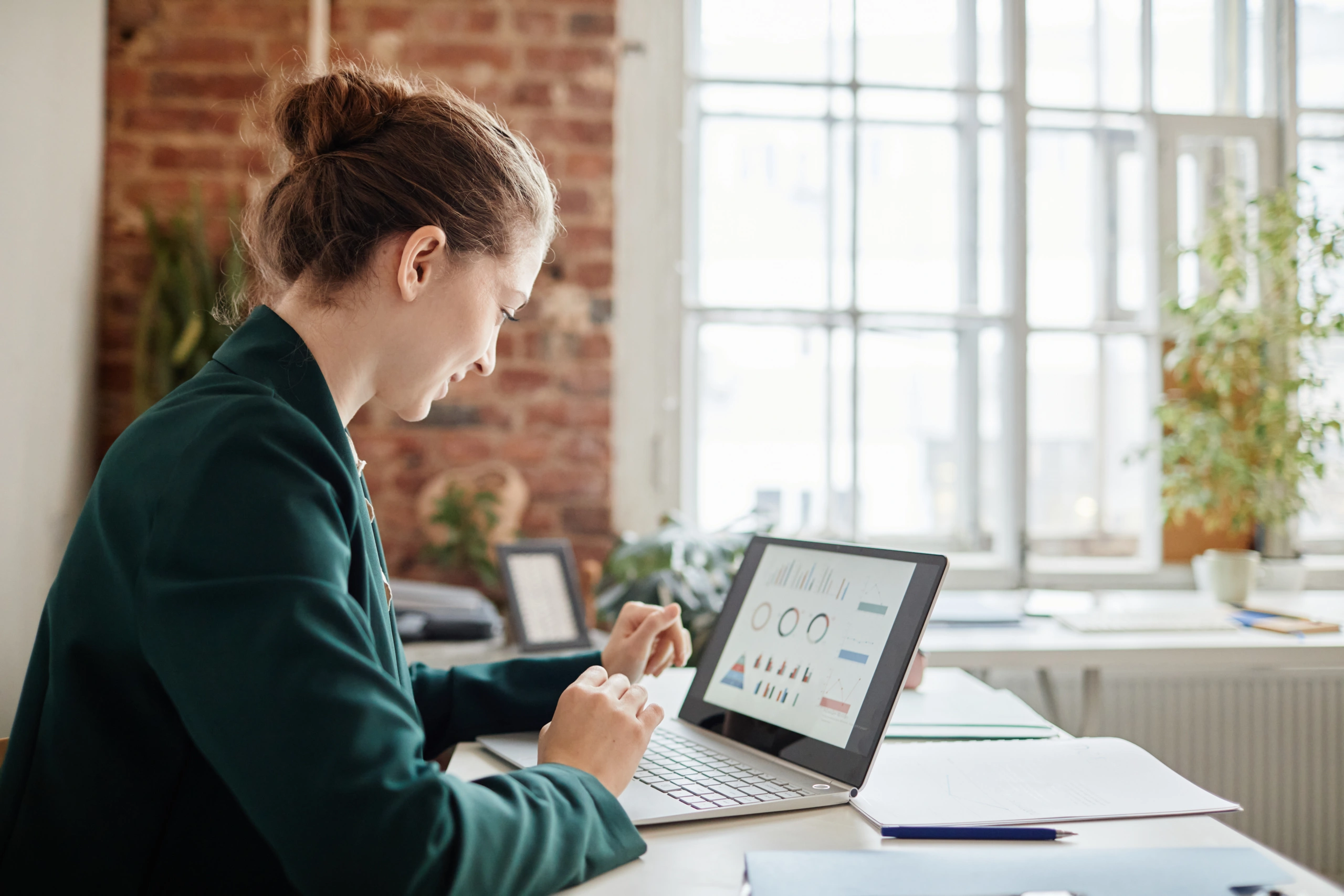 Business owner reviews financial dashboards on laptop in her office