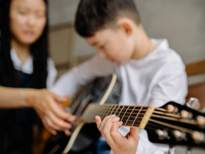 Young boy playing guitar with teacher