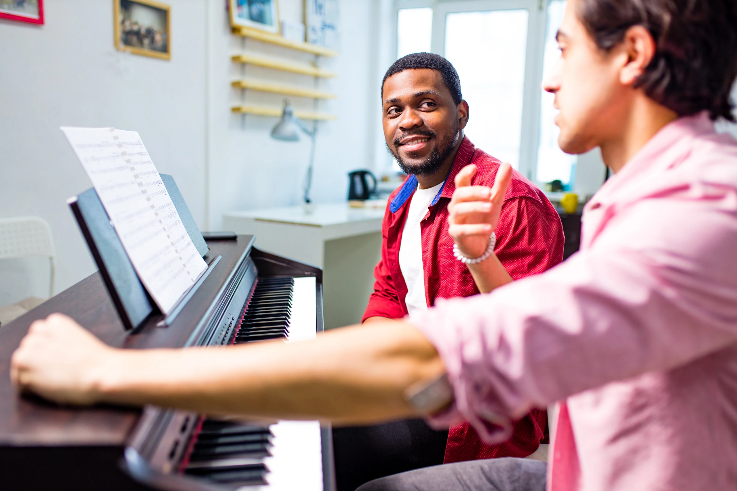 Music School Lesson Discussion – Opus1: Everything You Need to Run Your School in One Place Music school instructors discussing lesson content at a piano with reporting software - Opus1: Everything You Need to Run Your School in One Place