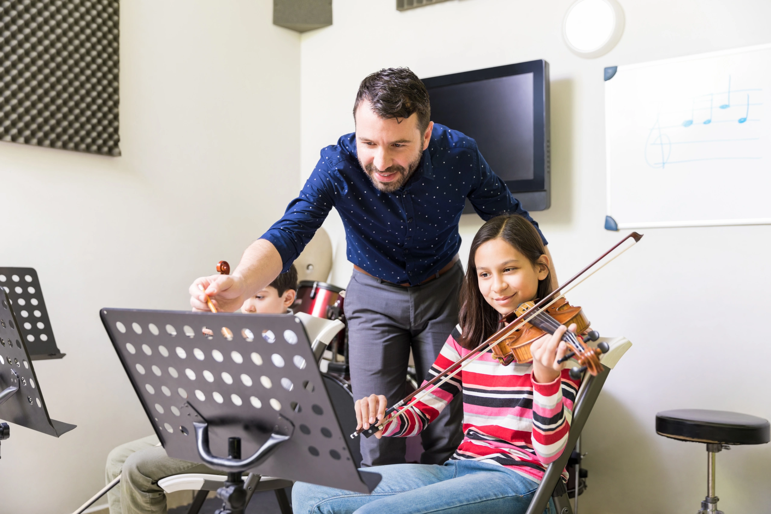 Music teacher with students using music school reporting software in classroom - Opus1: Everything You Need to Run Your School in One Place