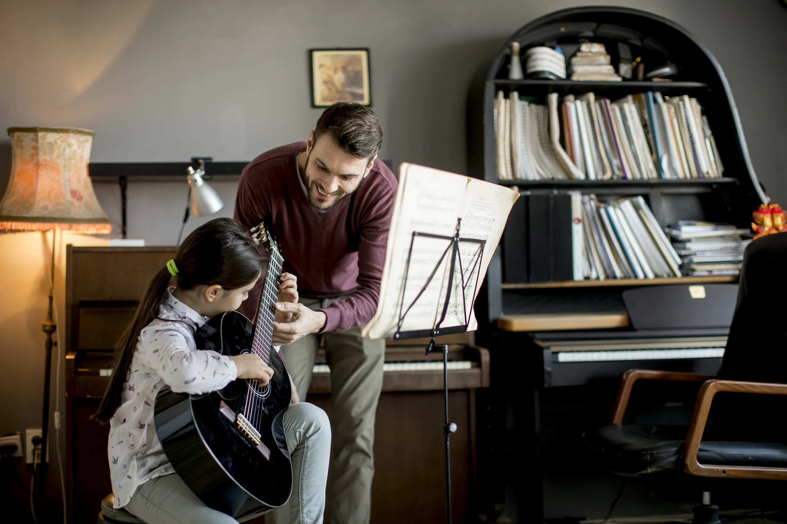 Music school teacher instructing student on guitar in studio - Opus1: Everything You Need to Run Your School in One Place