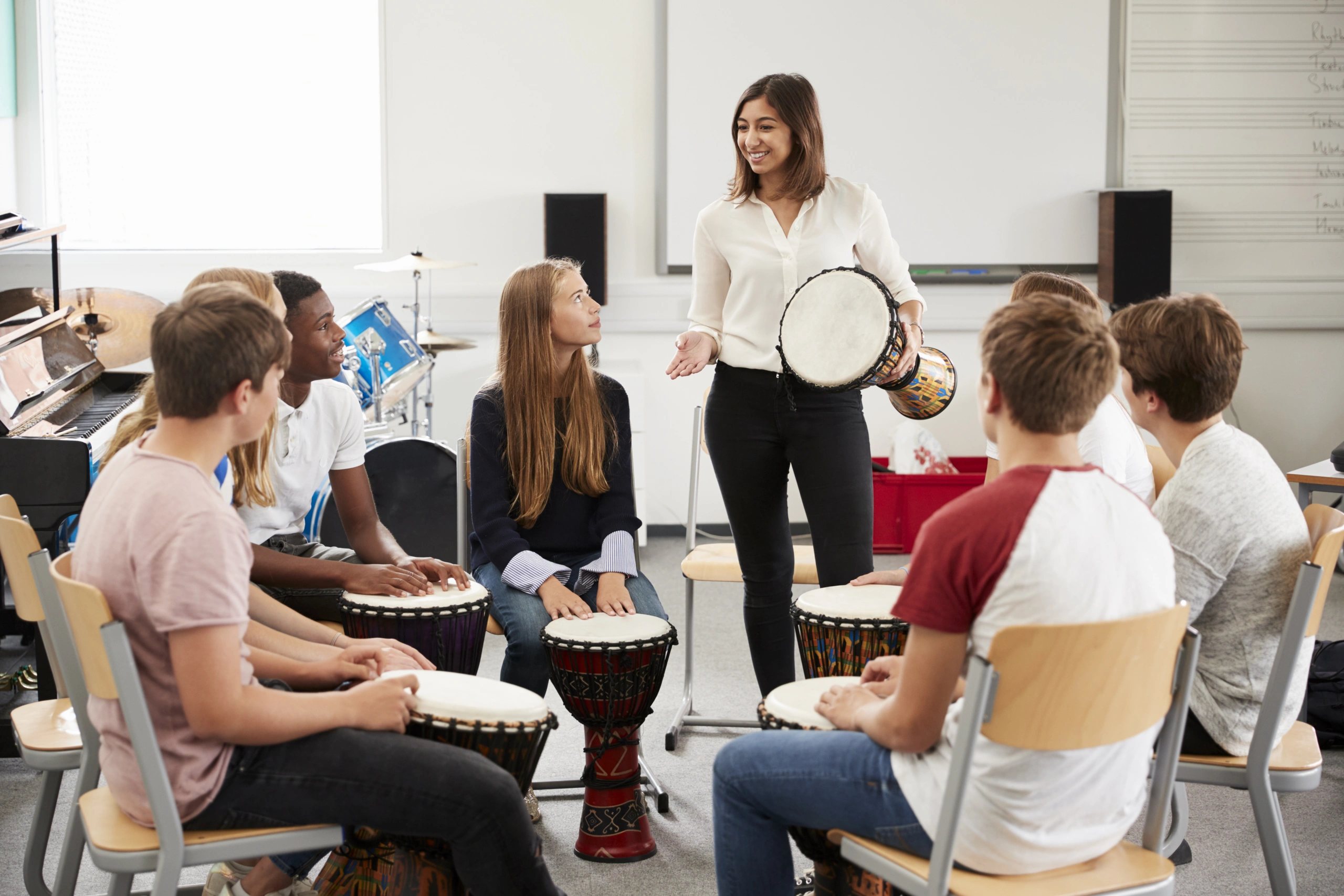 Music workshop with diverse group learning drumming techniques in a classroom - Opus1: Everything You Need to Run Your School in One Place