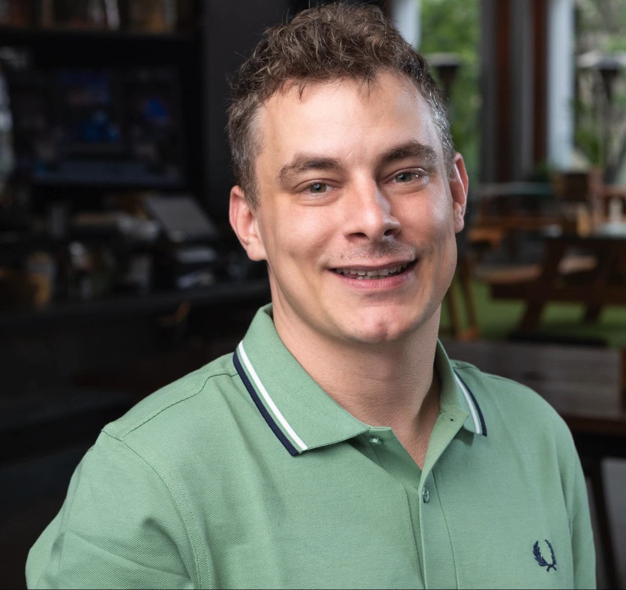 Man smiling in a green shirt at a music school industry report meeting - Opus1: Everything You Need to Run Your School in One Place